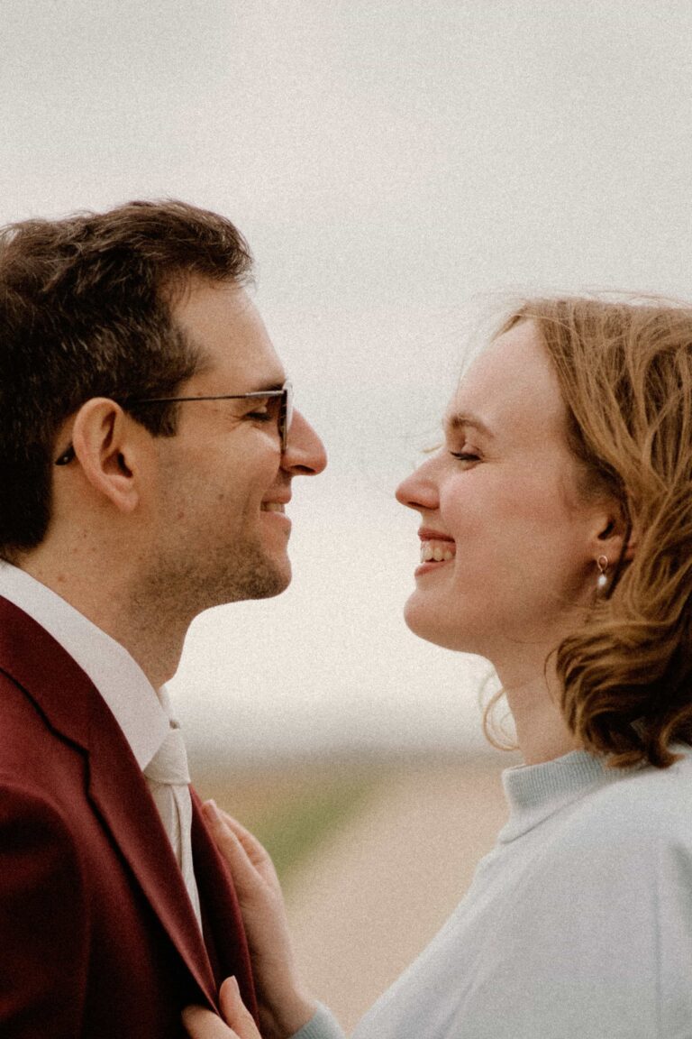 couple smiling at each other with sky in backround