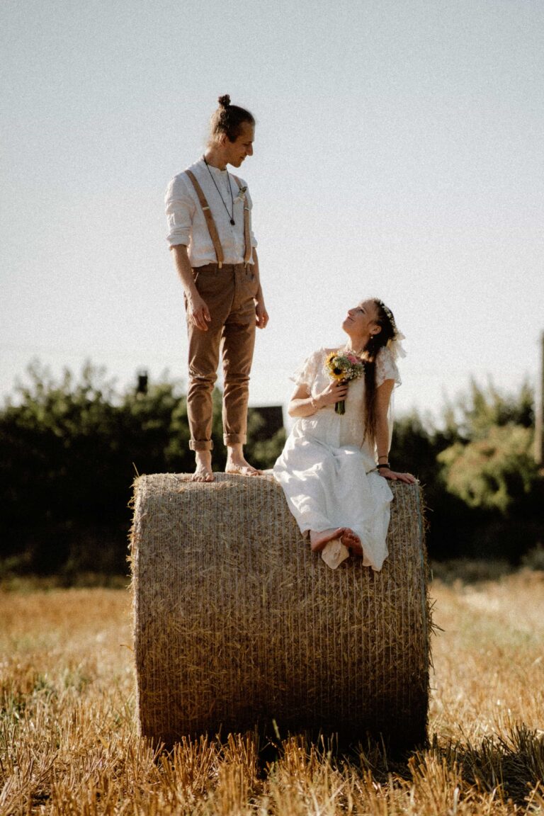 couple on straw bale with flowers in golden hor in vintage look