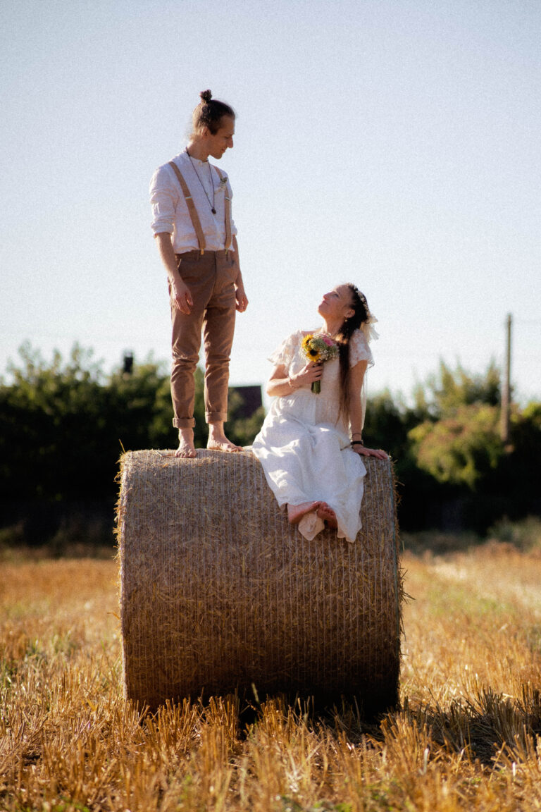 couple on straw bale with flowers in golden hor in vintage look